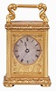 England, a very decorative miniature carriage timepiece, the gilt case with expertly engraved foliate ornament, the corners with reeded columns, surmounted by chased and engraved finials, the top with acanthus decorated handle, Roman numeral silvered dial with engraved center and gilt, engraved mask, blued steel Breguet style hands, 8 day timepiece movement with lever escapement, and spring barrel fixed to the front plate