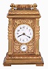 France, for Tiffany & Co., a Pillars style, petit sonnerie striking carriage clock with repeat, the glazed, gilt case with bright and matte surfaces, the base and cornice with cavetto and egg and dart moldings, the corners with acanthus decorated columns, and carrying handle also with foliate ornament, Arabic numeral white enamel dial with fretted, matte gilt foliate mask against a bright gilt background, blued steel distaff hands, 8 day time, strike, and alarm movement with lever platform, sounding petit sonnerie quarters in passing, with grand sonnerie repeating on demand, the base with strike/ silent lever