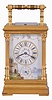 France, for the English market, a fine Pillars style repeating carriage clock with porcelain panels by Lucien Simonnet, the gilt case with stepped, molded base, the corners with fluted columns and Corinthian capitals supporting the molded cornice, the folding handle with turned ornament, case sides set with signed, polychrome enamel scenes depicting colorfully dressed young women in a garden, the Roman numeral dial surrounded by a landscape scene with castle ruins and floral garlands, blued steel distaff hands, 8 day time, strike, and alarm movement with lever platform, and repeating the last hour on demand, serial #2277