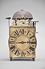 France, lantern clock, 30 hour, time and strike, weight driven movement, verge escapement with upward facing crown wheel, thread suspension with side-mounted pendulum, posted iron frame resting on short iron feet, brass front with integrated dial showing Roman numerals, single iron hand, topped by bell and pierced brass fronton.