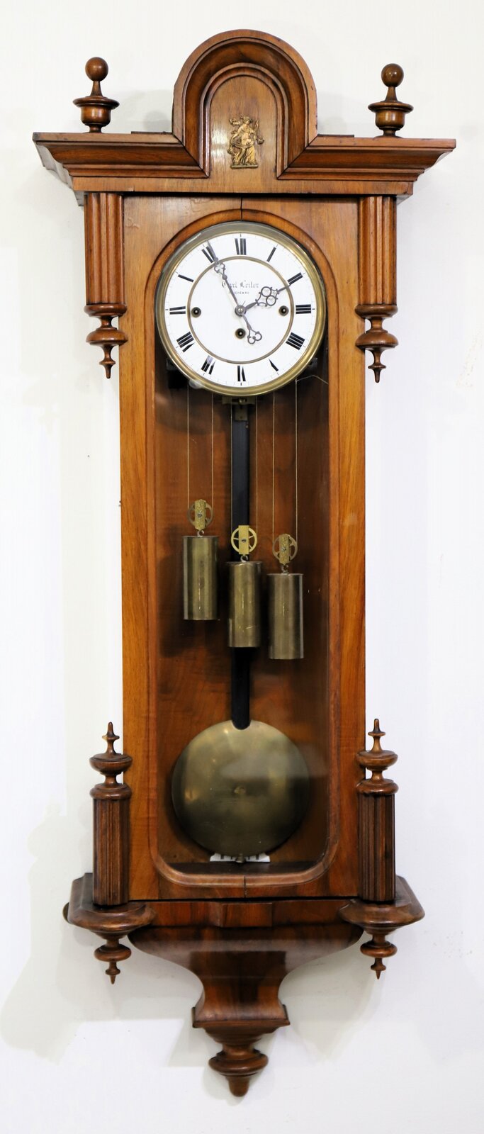 Carl Leiter three-weight Vienna, ca. 1885(?) A 45.5-inch Vienna in walnut with three old glasses, what appear to be the original finials, and a brass ornament on the crest. — Antique Clocks Price Guide