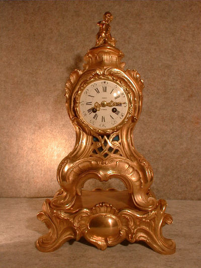 FRENCH CAST BRASS IN A GILT FINISH SERPENTINE STYLE MANTEL CLOCK ON AN ATTACHED BASE. CIRCA 1860-1880. — Antique Clocks Price Guide
