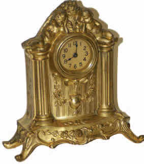American novelty clock, slightly under 9 inches tall, 2 cupids reclining above the dial. All original, running, has all its knobs and screws in place. — Antique Clocks Price Guide