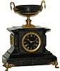 French black marble with gold-filled etchings on the front of the case; bronze frieze scenes on each side, of a woman and a cupid; gilt paw feet and bronze urn ornaments.