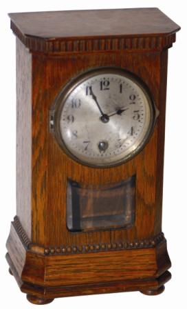 German miniature desk clock. A super little clock, only 8" high, ripple trim around the top and bottom, four wood bun feet, edges angled around the corners, and a full hinged and latching wood back door. — Antique Clocks Price Guide