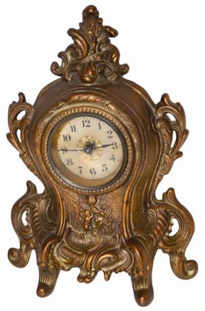 Warner metal novelty clock, 11" high, and in good condition. There are cupids below the dial, a flat glass, good hands and an unsigned dial. — Antique Clocks Price Guide
