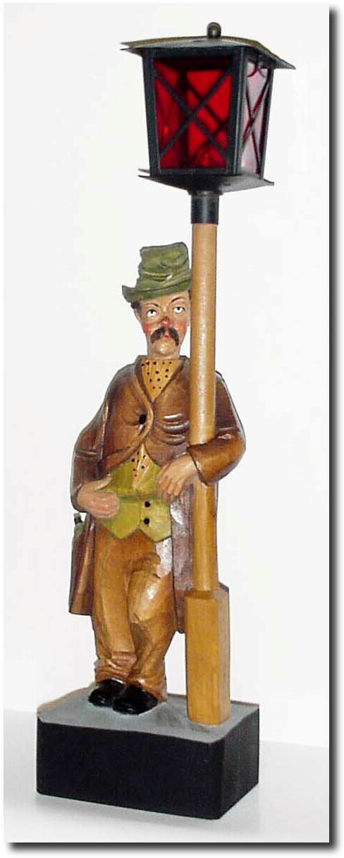 C.1960, German, "Whistling Drunk' , a carved figure leaning against a lamp post, with batteries in the base that light the lamp while he is whistling. — Antique Clocks Price Guide
