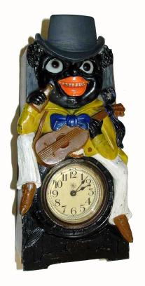 C.1910, German, Moving Eye Minstrel clock. They made these clocks with frogs and other performers, however this particular one is a black minstrel, complete with his fiddle, and booze bottle in his right hand. — Antique Clocks Price Guide