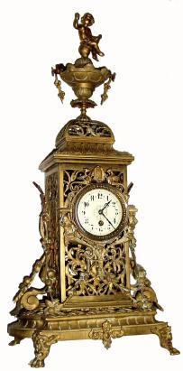 C.1890, French, Large Brass figural clock, 8-day time only, the oversize pierced case covered with vines and buds, the base with toed feet and the urn at top surmounted by a cherub. — Antique Clocks Price Guide