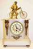 C.1900, French, Man and His Bicycle, atop a white alabaster case, with an 8-day time only pendulum movement, and with a porcelain dial with gilt brass center and case adornments. 