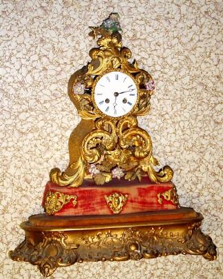 C.1840, French, Fanciful mantel clock on a gilt wood base [no dome], the embossed brass case accented with porcelain flowers [some missing]. — Antique Clocks Price Guide