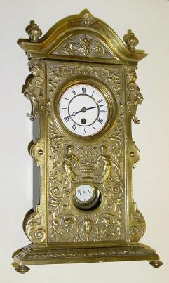 C.1890, German, Mini Shelf Clock, tall clock motif, a cast brass facade, base and crested top, the well made 8-day movement with 7 wheels in the train, going for a week. — Antique Clocks Price Guide