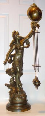 C.1890, French, Large Patinated Spelter swinging arm clock, the female statue of Fortune, her right foot on a winged wheel of fortune, and her left arm supporting the clock. The timepiece arm with the movement contained within the large ball and the entire arm swinging without apparent impulse. — Antique Clocks Price Guide
