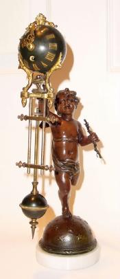 C.1890, French, Miniature Swing Clock, a small statue of cupid on a star studded globe, holding a bow in his left hand and the clock support in his right hand. — Antique Clocks Price Guide