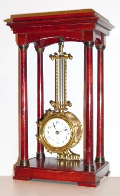 C.1900, German, Gustav Becker, Novelty Swinging clock, 3-day, the movement at the bottom of a grid pendulum, mounted to the ceiling of a mahogany stained wooden portico. — Antique Clocks Price Guide