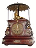 C.1890, German, Rare Flying Pendulum timepiece, a walnut and walnut stained case with lots of cast brass trim, a child at the top with outstretched hand trying to catch the flying ball at the end of the pendulum, the arm and string concealed beneath the umbrella and adding to the eye appeal of the clock.