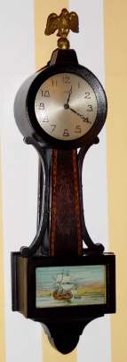 C.1915, New Haven Clock Co., 12-day banjo timepiece, silk screened harbor scene and wooden throat. We think this a later variation on the Willis, as it is 18" and with similar profile. — Antique Clocks Price Guide