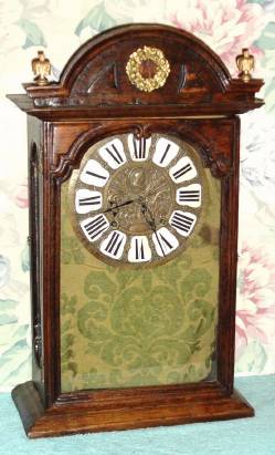 C.1790, French, 8-Day, Shelf clock with silk thread suspension and short span tic-tac escapement, unsigned.  Cast brass dial with image of a queen, and 12 individual cartouche numerals. — Antique Clocks Price Guide