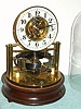 C.1912, English, Reason Mfg, Brighton, Electrically impulsed balance wheel clock, a skeleton layout on a mahogany base, under glass dome, made to the 1911 patent design of Thomas John Murday.