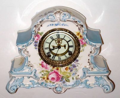 C.1904, Ansonia Clock Co., Royal Bonn LA NORD, porcelain china clock in tu-tone sky blue and white with magenta colored rose bottom center, plus gold highlights, the porcelain dial with open escapement. — Antique Clocks Price Guide