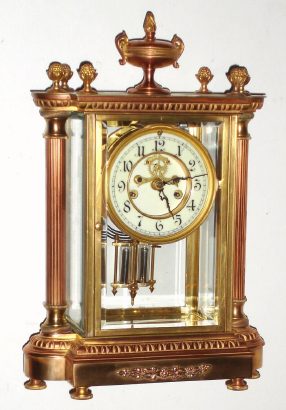 C.1908, Waterbury Clock Co., SEVRES, 4-glass crystal regulator, flanked by 2 free standing columns and surmounted my a decorative urn, also with open escapement on the porcelain dial. — Antique Clocks Price Guide
