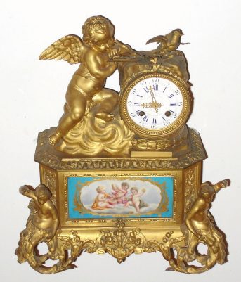 C.1880, Vernet, 38 Rue du Bac, Paris, French, Ormolu figural clock: Cherub and mermaid castings and three porcelain inserts with an 8-day time and strike movement. — Antique Clocks Price Guide