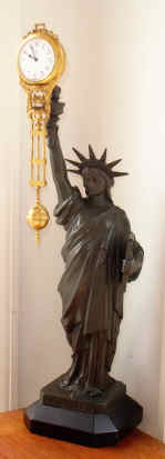 C.1900, German, Junghans, STATUE OF LIBERTY swinging arm clock, 8-day, figure holding a tablet inscribed "4th July 1776".. — Antique Clocks Price Guide