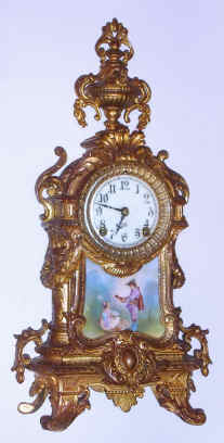 C.1900, Ansonia Clock Co., ROYAL, gilt white metal mantel clock, with porcelain plaque in the base of a gentleman playing the mandolin to a lady. — Antique Clocks Price Guide