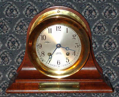 C.1991, Chelsea Clock Co., Boston, CHELSEA model 4.5" ships bell clock on mahogany stand, serial No. 876366, with presentation plaque, hinged bezel, button latch. — Antique Clocks Price Guide
