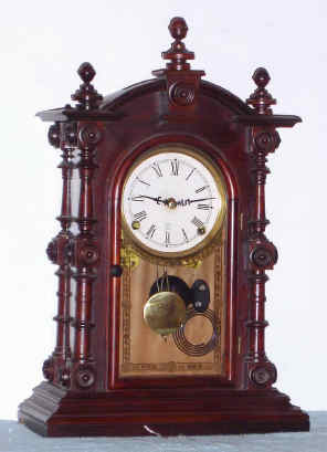 Mixed lot, C.1880 Welch "Patti" rosewood case, now with a C.1910 large kitchen style movement, 8-day, installed onto a piece of pressed board, added to bring the minute shaft out to the correct length. — Antique Clocks Price Guide