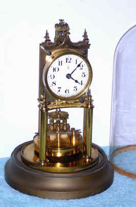 C.1905, German, Gustav Becker, 400-day Disc pendulum clock with glass dome, and with original beat set adjuster on top and gilt floral trim piece under the dial, serial No. 199. — Antique Clocks Price Guide