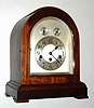 C.1910, German, Junghans, Wurtemberg, Westminster chime mantel clock in a round gothic mahogany case, button latch door and beveled glass front, arched silvered dial with subsidiary rings for F/S and Chime/Silent.