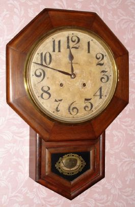 Ansonia Clock Co., short drop octagon wall clock, time and strike, 8-day, walnut veneer case. C. 1910. — Antique Clocks Price Guide