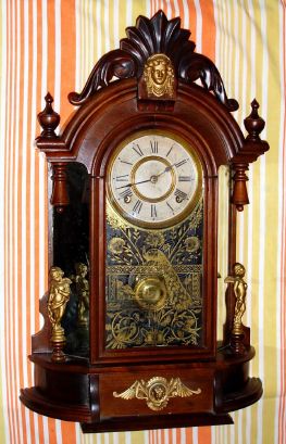 Ansonia Clock Company, Ansonia Conn. "TRIUMPH" model, 8-day brass time and strike mvt in black walnut mirror-sided case flanked by two cupids shelf clock, spring driven. C. 1880. — Antique Clocks Price Guide