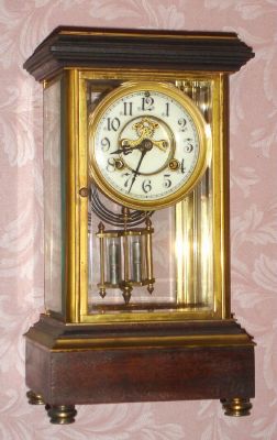 Waterbury Clock Co., FLANDERS, mahogany and brass crystal regulator, with open escapement on the dial and with 2-jar pendulum, and with cast gilt bezel. C.1906. — Antique Clocks Price Guide