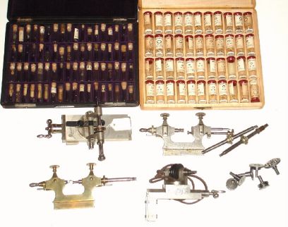 Box lot consisting of: a case with an assortment of white and yellow GF jump rings. A case with about 72 small corked glass vials, only 5 with small watch screws and other assorted small parts. Finally a box with 3 lathe attachments for pivot polishing, very nicely made and a demagnetizer — Antique Clocks Price Guide