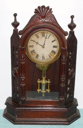 Ansonia Clock Co., 8-day time and bell strike, walnut mantel clock, fancy with pierced sides. Circa 1874. We could not find this model in the catalog, but a similar example: "The Turret" can be found there. — Antique Clocks Price Guide