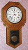New Haven Clock Co, New Haven Conn, "BANK" calendar model, long drop embossed oak school clock, 8 day time mvt in oak case with 12" dial, spring driven. C. 1910.