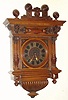 Austrian, Walnut cartel clock, silk thread suspension, signed Johann Kriwsky, with a brass cut out chapter ring over a wooden dial plate, large 8-day movement, gong strike, spring. The walnut case with deeply carved 3/4 columns and with finely detailed lions above. C.1875.