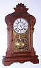 Waterbury Clock Co., MELROSE, walnut gingerbread clock, with 8-day time and gong strike spring movement, and nickeled pendulum with glass center. C.1881.