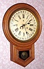 Waterbury Clock Co, "12-Inch Round Head Drop" with concentric calendar. oak cased, 8-day time and strike. C.1900.