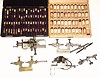 Box lot consisting of: a case with an assortment of white and yellow GF jump rings. A case with about 72 small corked glass vials, only 5 with small watch screws and other assorted small parts. Finally a box with 3 lathe attachments for pivot polishing, very nicely made and a demagnetizer