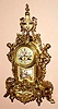 French, S. Marti and Cie, for J. E. Caldwell, Philadelphia, an architectural fantasy with swags, female caryatids and flower adornments, all in cast brass, now polished, and with a porcelain panel dial showing a winged cherub, a plaque below the dial showing a pair of lovers and a ladies' bust on the porcelain urn at top, 8-day time and strike, spring movement. C.1900