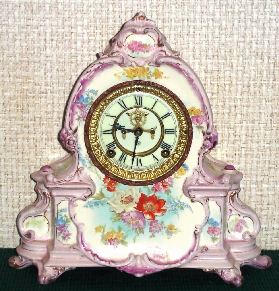 Ansonia Clock Co., C.1904, Royal Bonn, "LA MANCHE" porcelain china cased clock, with 8-day, gong strike mov't with open escapement on porcelain dial. Case a very light violet shade, and with floral decorations to the sides. — Antique Clocks Price Guide