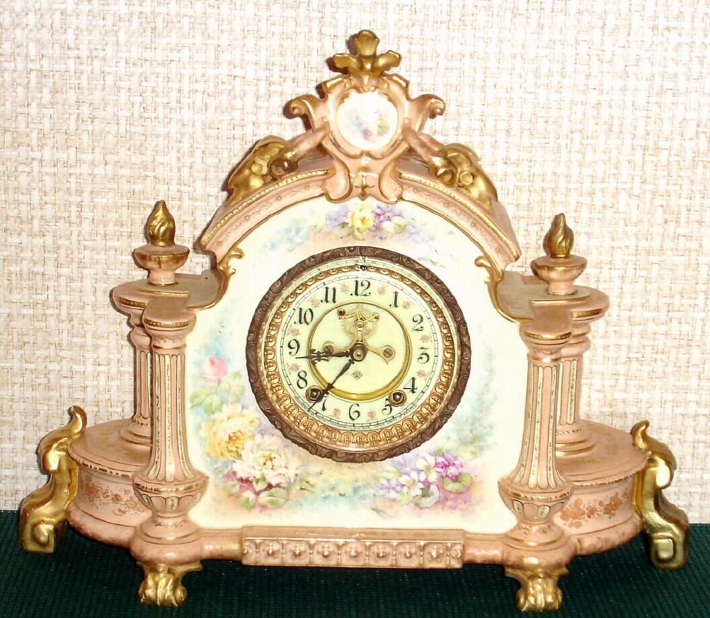 Ansonia Clock Co., C.1895, Royal Bonn, "LA CHAMPAGNE" porcelain china cased clock, with 8-day, gong strike mov't with open escapement on porcelain dial. Color is beige with gold highlights and multi color floral decorations. — Antique Clocks Price Guide