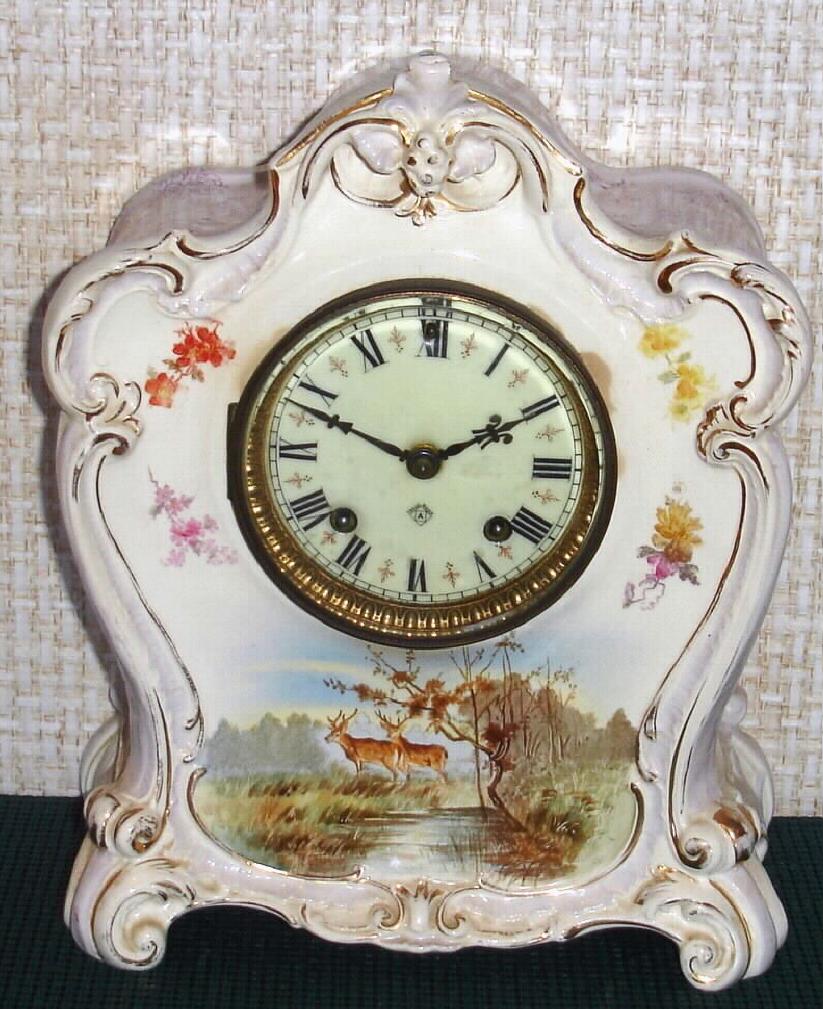 Ansonia Clock Co., C.1895, Royal Bonn, "LA MURE" porcelain china cased clock, with 8-day, gong strike mov't with hand painted scene of 2 deer at a pond in the wilderness, solid porcelain dial, with red trim between numerals. — Antique Clocks Price Guide