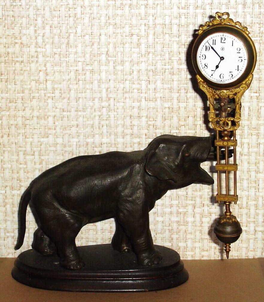C.1910, German, Junghans, ELEPHANT swing clock, the clock contained in the gilded "arm" supported by his trunk, back wind, center set, and with porcelain dial, 8-day. — Antique Clocks Price Guide