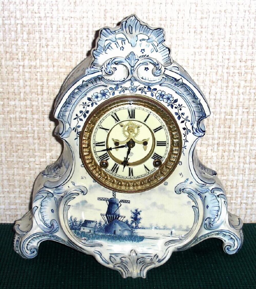 Ansonia Clock Co., C.1905, Royal Bonn, "LA NORMANDIE" porcelain china cased clock, with 8-day, gong strike mov't with open escapement on porcelain dial, in a Blue Delft case with windmills and sailing ships. — Antique Clocks Price Guide
