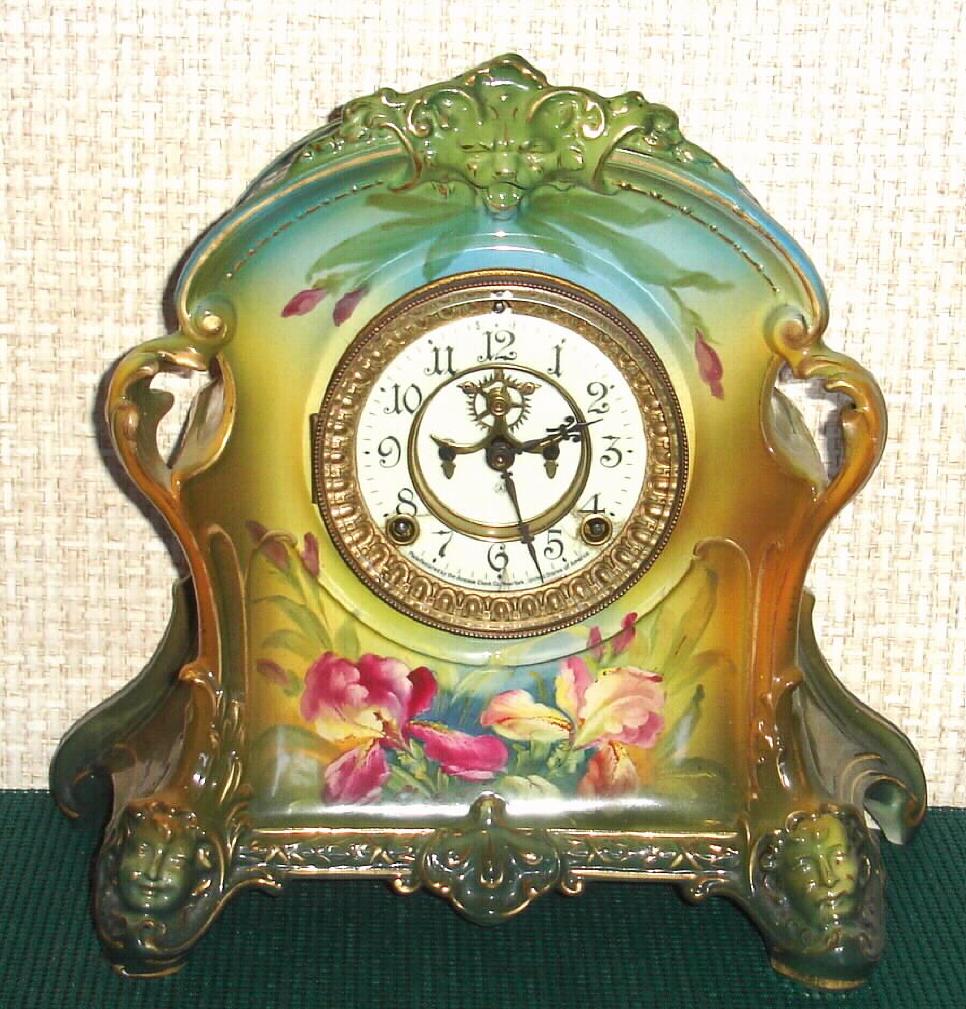 Ansonia Clock Co., C.1905, Royal Bonn, "LA PLATA" porcelain china cased clock, with 8-day, gong strike mov't with open escapement on porcelain dial, in a multi-colored case, aqua/green top, yellow center + dark green at base, with purple and yellow iris decorations and gold highlights. — Antique Clocks Price Guide