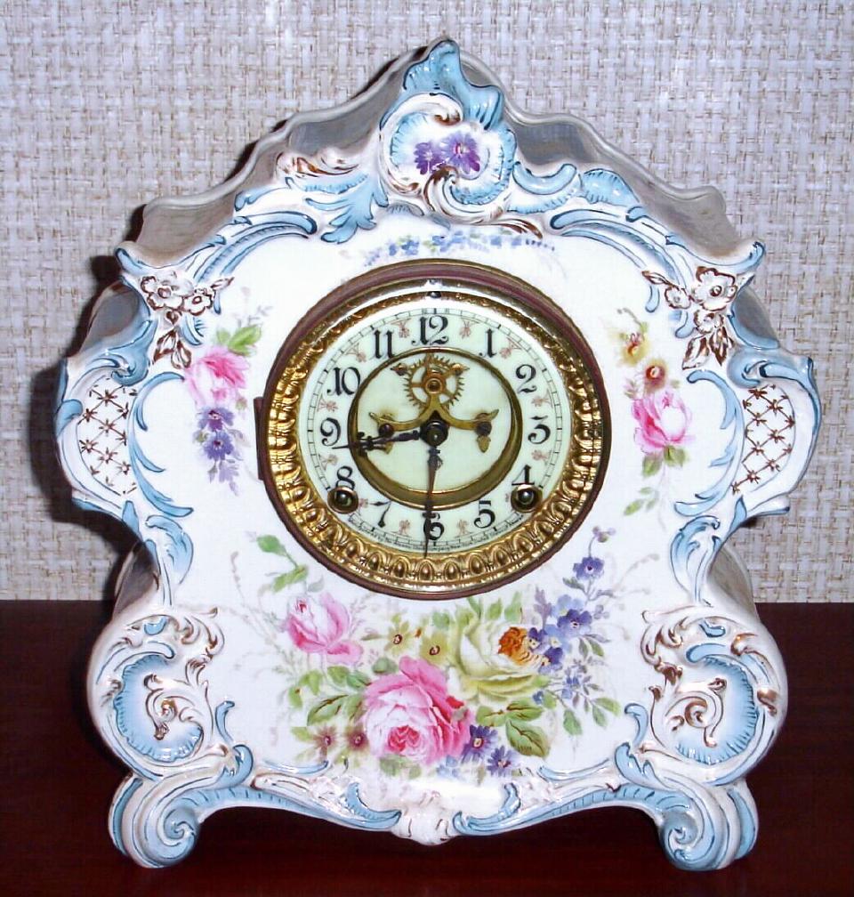 Ansonia Clock Co., C.1905, Royal Bonn, "LA VOGUE" porcelain china cased clock, with 8-day, gong strike mov't with open escapement on porcelain dial, in a creamy case with light blue accents and gold highlights, and with multi colored floral trim on the case front and sides. — Antique Clocks Price Guide